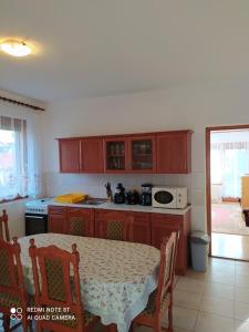 a kitchen with wooden cabinets and a table with a tablecloth on it at Anna Ilona Vendégház in Badacsonytomaj