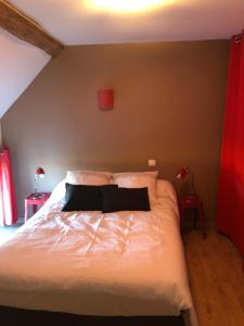 1 dormitorio con cama blanca y pared roja en Gîte La Ferranderie, en Saint-Hilaire-de-Gondilly