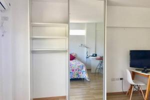 ブエノスアイレスにあるLUMINOSO Y MODERNO EN CABALLITOの白い棚、デスク、ベッドが備わる客室です。