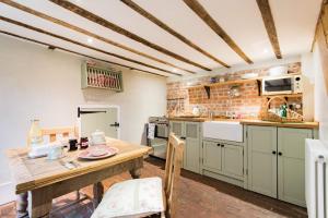 une cuisine avec une table en bois et une salle à manger dans l'établissement Oast Barn Cottage by Bloom Stays, à Faversham