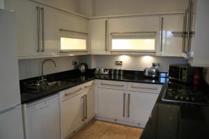 una cocina con armarios blancos y encimeras negras en Shanklin Manor en Shanklin