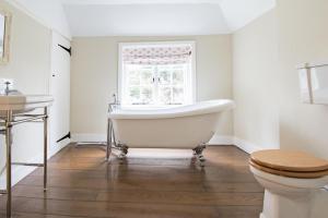ein Badezimmer mit Badewanne und Toilette und einem Fenster in der Unterkunft Oast Barn Cottage by Bloom Stays in Faversham + 12 Fotos