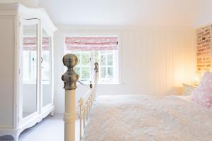 a white bedroom with a bed and a window at Oast Barn Cottage by Bloom Stays in Faversham