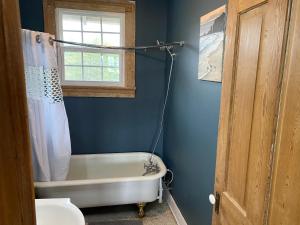 a bathroom with a tub and a toilet and a window at Uptown Treehouse in New Orleans
