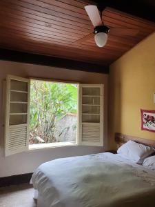 a bedroom with a large bed and a window at "Chalé Balines Oroboro" 1 - Casa com jardim de 150 m e cozinha completa em Macacos in Macacos