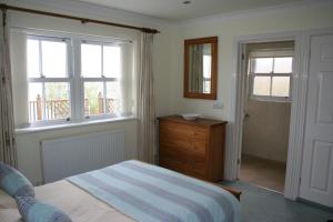 a bedroom with a bed and a dresser and windows at The Priory in Shanklin