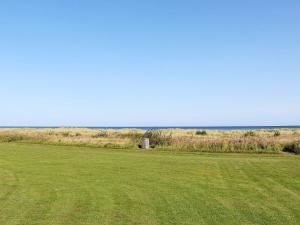 un campo con césped verde y el océano en el fondo en 6 person holiday home in Hadsund, en Hadsund