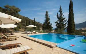 een zwembad met stoelen en tafels en een resort bij Lefkas Petra in Ayios Nikitas