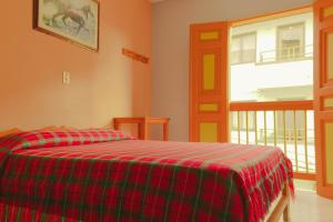 a bedroom with a bed with a red and green plaid blanket at Hotel Felicina in Jericó