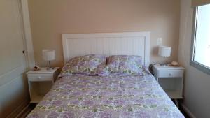 a bedroom with a bed with a purple comforter and two night stands at Deptos MORE II in Puerto Madryn
