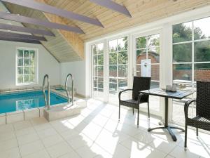a living room with a pool and a table and chairs at 14 person holiday home in Ulfborg in Husby