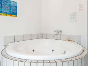 a white bath tub in a bathroom with a tile wall at 14 person holiday home in Ulfborg in Husby