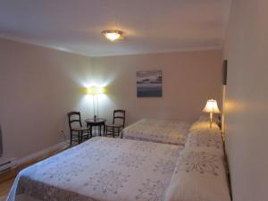 a bedroom with two beds and a table with chairs at Shepody Bay Inn in Hopewell Cape