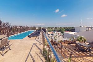 a balcony with chairs and a swimming pool on a building at Hotel CARPE DIEM Tulum by Nah Hotels in Tulum