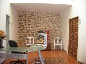 Habitación con pared de piedra y mesa de cristal. en Hostel El Castillo, en Ariñón