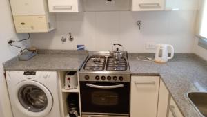 uma cozinha com um fogão e uma máquina de lavar roupa em Deptos MORE II em Puerto Madryn