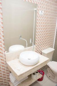 La salle de bains est pourvue d'un lavabo, de toilettes et d'un miroir. dans l'établissement Hotel Morada do Mar, à Guarujá