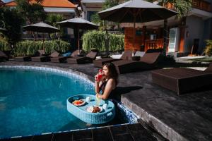 una mujer sentada junto a una piscina con un tazón de comida en Pandawa Resort & Spa Seaview, en Nusa Penida