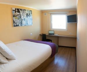 Schlafzimmer mit einem Bett und einem Schreibtisch mit einem Laptop in der Unterkunft Hotel Modular Express Calama in Calama