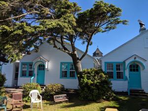 a house with a tree and chairs in the yard at Hillcrest Inn in Seaside