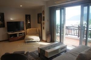 sala de estar con sofá, TV y balcón en Khanom Beach Residence Sea & Mountain View - 1 Bedroom en Ban Na Dan