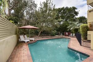 a swimming pool with chairs and an umbrella at 20 Steps to the Sand! in Mooloolaba