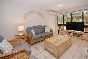 a living room with a couch and a tv at 20 Steps to the Sand! in Mooloolaba