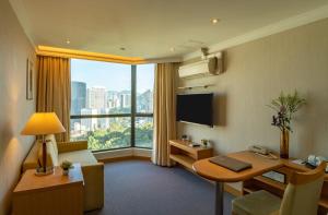 Habitación de hotel con escritorio y ventana grande. en Bishop Lei International House, en Hong Kong