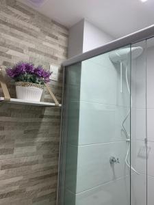 a bathroom with a glass shower with purple flowers on a shelf at Espetacular Flat em Miramar in João Pessoa