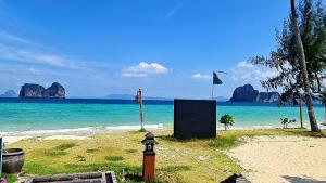 a beach with rocks in the water and a flag at Thanya Beach Resort - SHA Plus in Ko Ngai