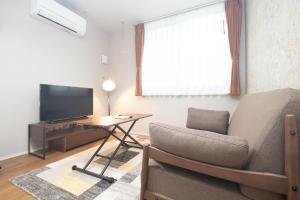 Una sala de estar con un sofá y un televisor. en LA CHIC Stay Hakata Ⅱ, en Fukuoka