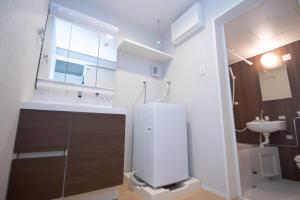 Un baño con lavabo, inodoro y espejo. en LA CHIC Stay Hakata Ⅱ, en Fukuoka