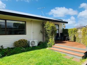 a house with a wooden deck and a patio at Aotearoa Lodge in Whitianga