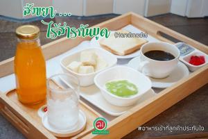 a tray of food with a drink and a cup of coffee at Lertnimit Hotel in Chaiyaphum