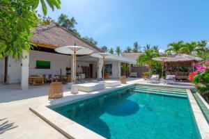 a pool with chairs and umbrellas next to a villa at Villa Butterflydream in Karangasem