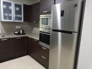 a stainless steel refrigerator in a kitchen with brown cabinets at Le Sifah - Marina View Apartments & Villa in As Sīfah