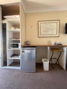 a kitchen with a refrigerator and a desk with a microwave at Motel Margeurita in Queanbeyan