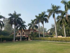 a house with palm trees in front of a yard at Ashok Country Resort in New Delhi