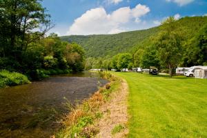 ein Fluss neben einem Campingplatz mit einem Berg in der Unterkunft Chalet Gringlee in Goebelsmuhle