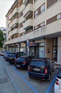 una fila di auto parcheggiate in un parcheggio di fronte a un edificio di Ca Re Vespucci a Pordenone