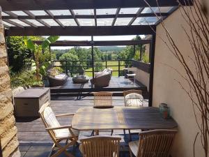 a wooden table and chairs on a wooden deck at Le Cottage Belmontais, maison individuelle, vue panoramique sur la rivière in Beaumont-sur-Sarthe