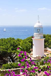 un faro blanco con un barco en el agua en Bel Appartement vue Mer, en Roses