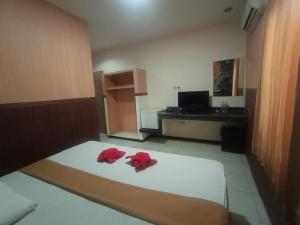 a bedroom with a bed with two red pillows on it at Votel Hotel Tulungagung in Tulungagung