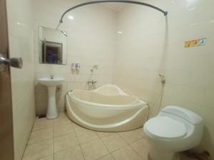 a bathroom with a tub and a toilet and a sink at Votel Hotel Tulungagung in Tulungagung