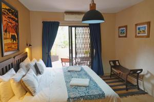 a bedroom with a large bed and a chair at Tau @ Kruger in Marloth Park