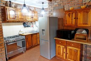 a kitchen with wooden cabinets and a stainless steel refrigerator at Tau @ Kruger in Marloth Park