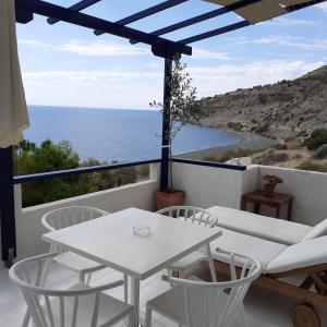 a white table and chairs on a balcony with the ocean at Big Blue Studios Myrtos in Myrtos