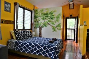 ein Schlafzimmer mit einem Bett mit einem Wandbaum in der Unterkunft Sanpopo Tree Top Cottage - A Gold Standard Tourism Approved Vacation Home in San Ignacio