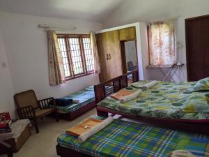 een slaapkamer met 2 bedden, 2 stoelen en ramen bij Siderbhan Homestay in Chikmagalūr +33 foto's