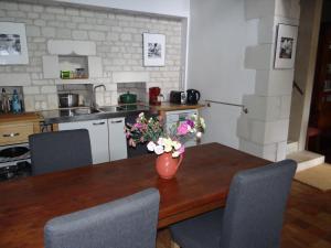 una cocina con una mesa con un jarrón de flores. en gîte du manoir des roches, en Saires